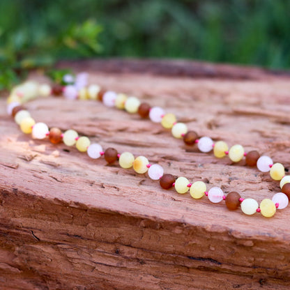 Amber Necklace Multi amber raw and Rose Quartz Baby 32cm Our Amber necklaces imported directly from Lithuania, the home of Baltic Amber and the Baltic Sea, where they are beautiful handmade. Baltic Amber necklaces help with teething symptoms as well as looking great.