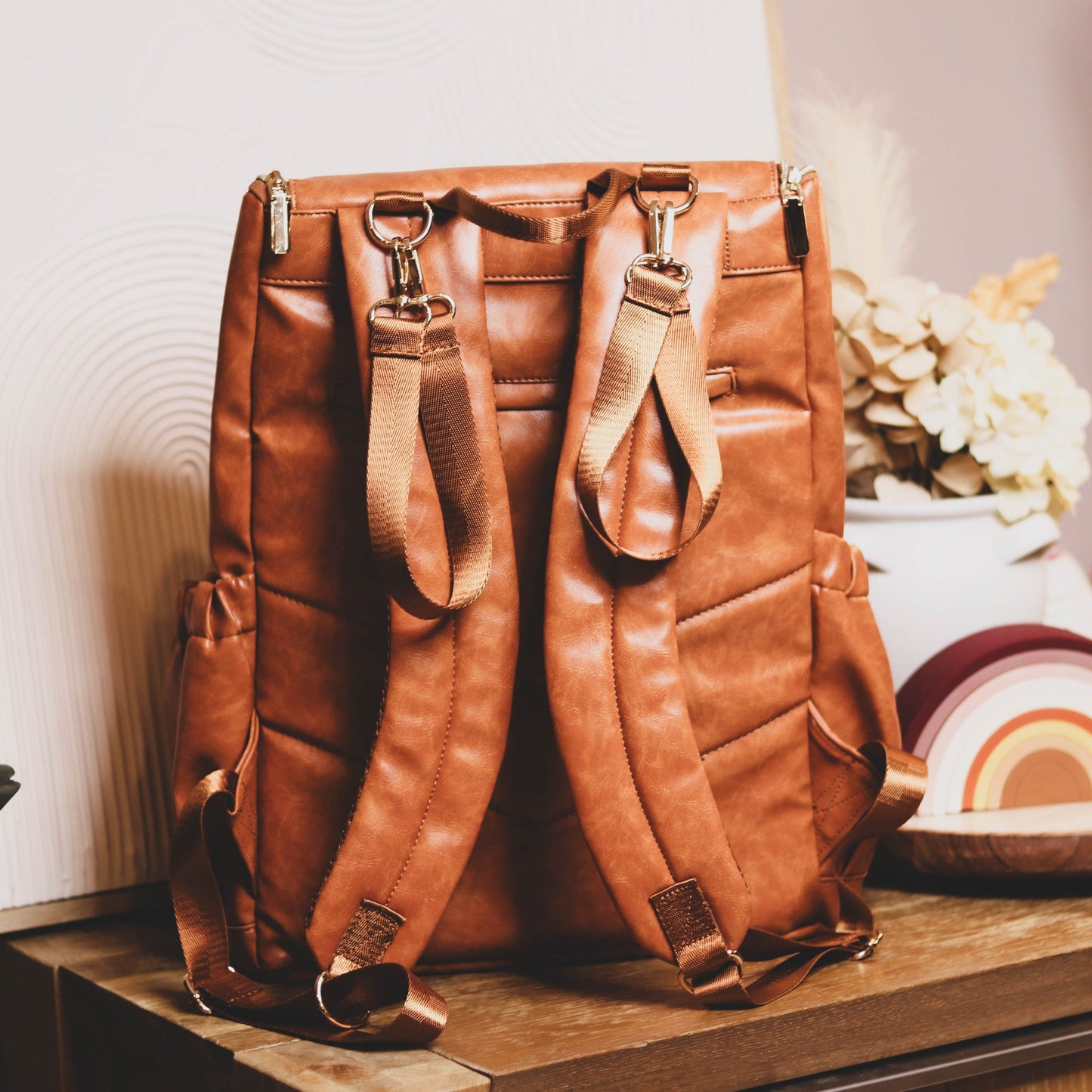Faux Leather Nappy Bag Backpack - Luxe Tan Brown Our Faux Brown Leather Nappy Bag adds a sophisticated look to an everyday essential, stylish, functionality for everyday use. Nappy bag backpacks are an essential part of the babies haul when leaving the house – A Must have! An Amazing quality, so soft to touch, multi functional backpack, perfect for busy parents.