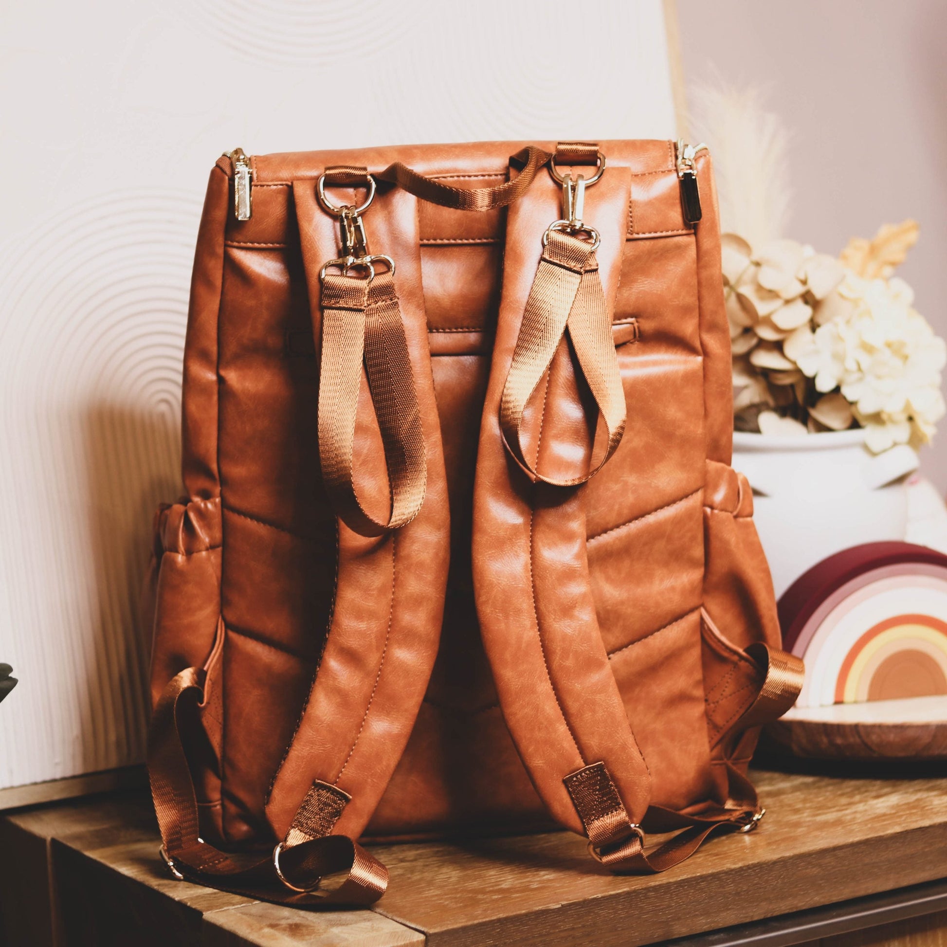 Faux Leather Nappy Bag Backpack - Luxe Tan Brown Our Faux Brown Leather Nappy Bag adds a sophisticated look to an everyday essential, stylish, functionality for everyday use. Nappy bag backpacks are an essential part of the babies haul when leaving the house – A Must have! An Amazing quality, so soft to touch, multi functional backpack, perfect for busy parents.