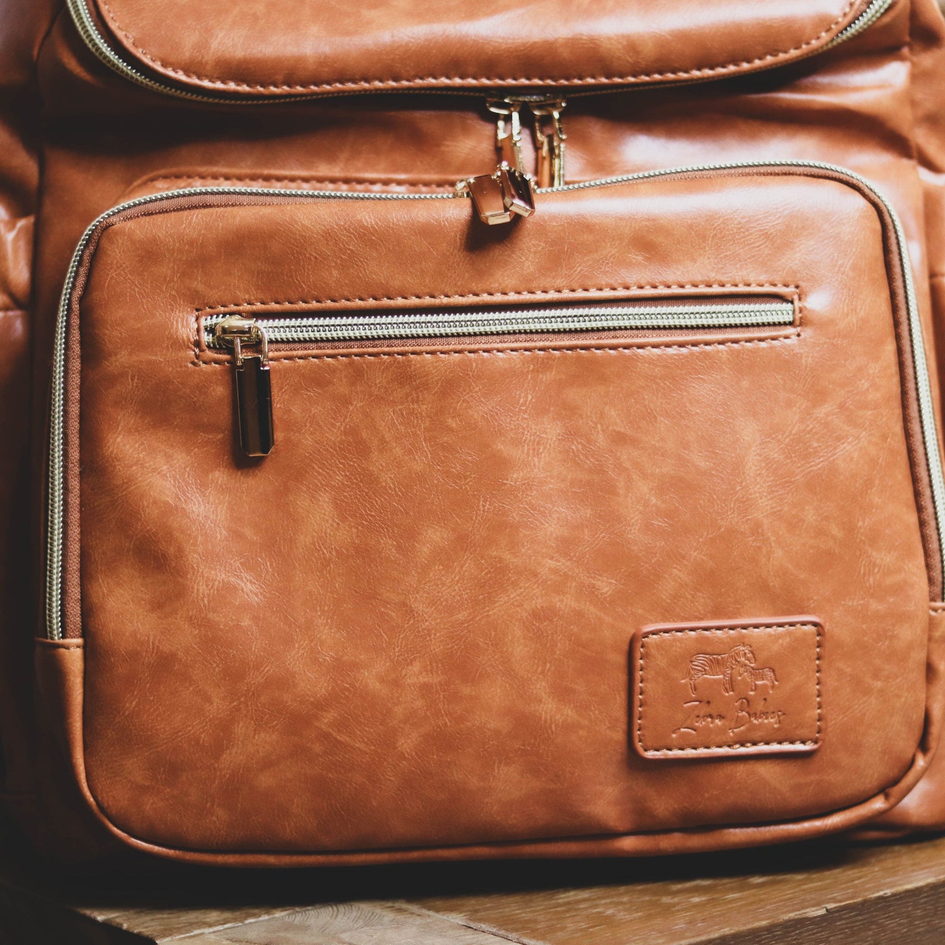 Faux Leather Nappy Bag Backpack - Luxe Tan Brown Our Faux Brown Leather Nappy Bag adds a sophisticated look to an everyday essential, stylish, functionality for everyday use. Nappy bag backpacks are an essential part of the babies haul when leaving the house – A Must have! An Amazing quality, so soft to touch, multi functional backpack, perfect for busy parents.