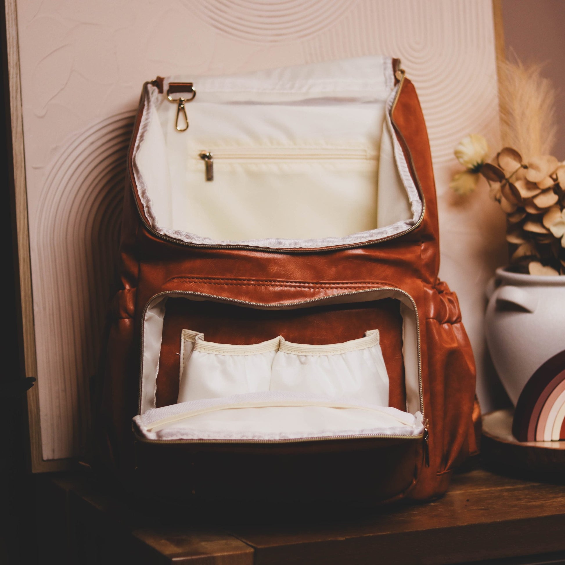 Faux Leather Nappy Bag Backpack - Luxe Tan Brown Our Faux Brown Leather Nappy Bag adds a sophisticated look to an everyday essential, stylish, functionality for everyday use. Nappy bag backpacks are an essential part of the babies haul when leaving the house – A Must have! An Amazing quality, so soft to touch, multi functional backpack, perfect for busy parents.